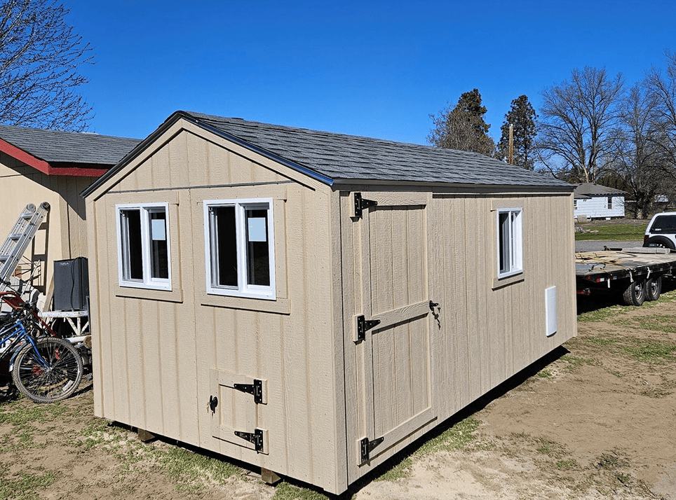 Beige wooden shed with three windows.