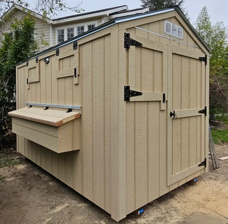 Beige wooden shed with side and front doors.