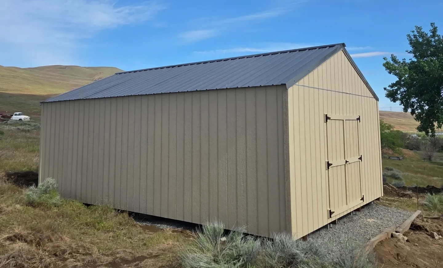 Beige wooden shed in a rural setting.